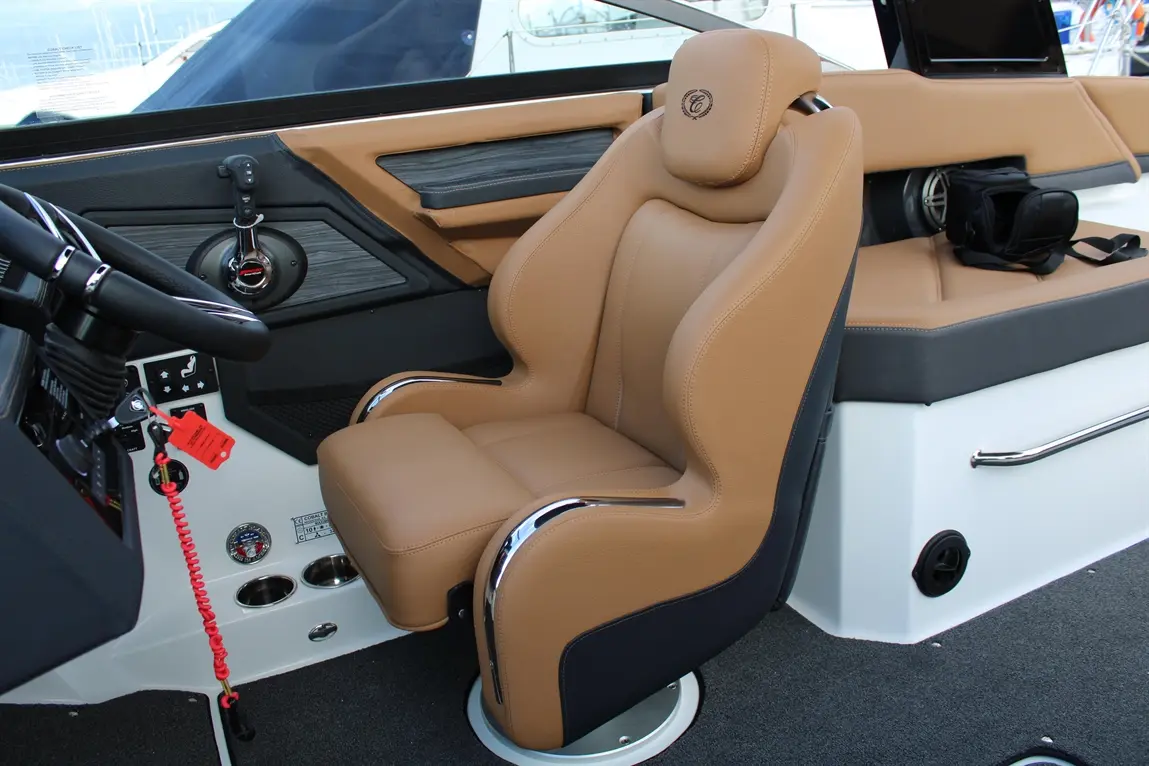 Sleek boat interior featuring a tan leather captain's seat, steering controls, and modern nautical elements.